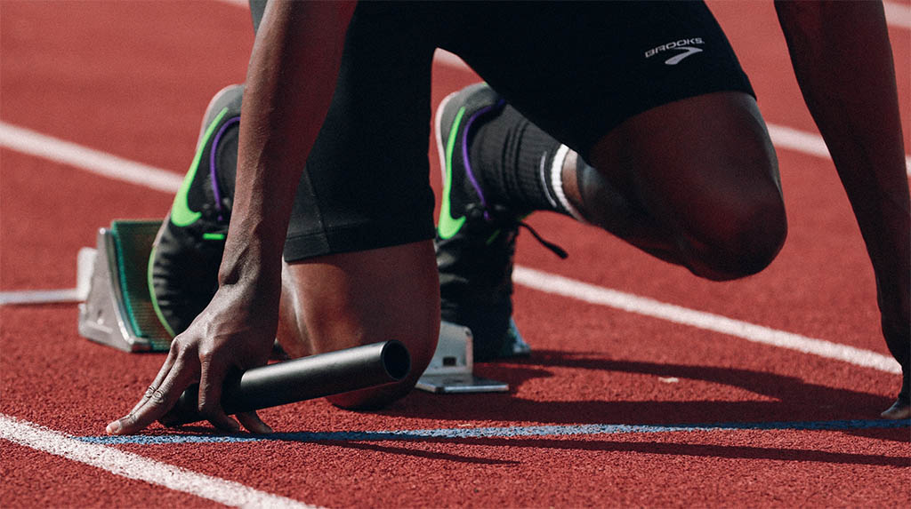 Track runner holding baton at starting line for race