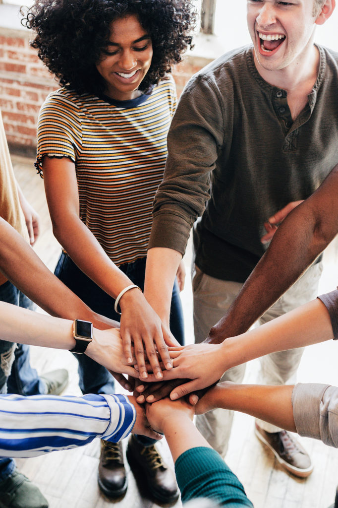 Group of diverse team layering hands on top of each other