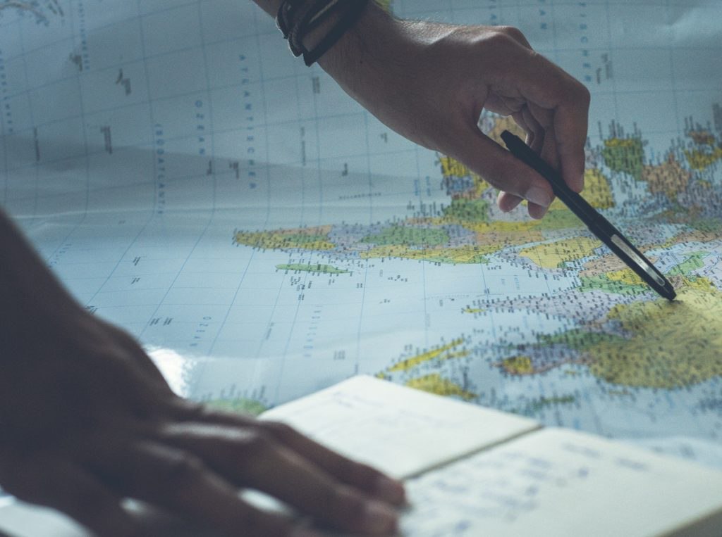 Focused view of a person pointing to a world map to evaluate opportunities to scale marketing growth strategies