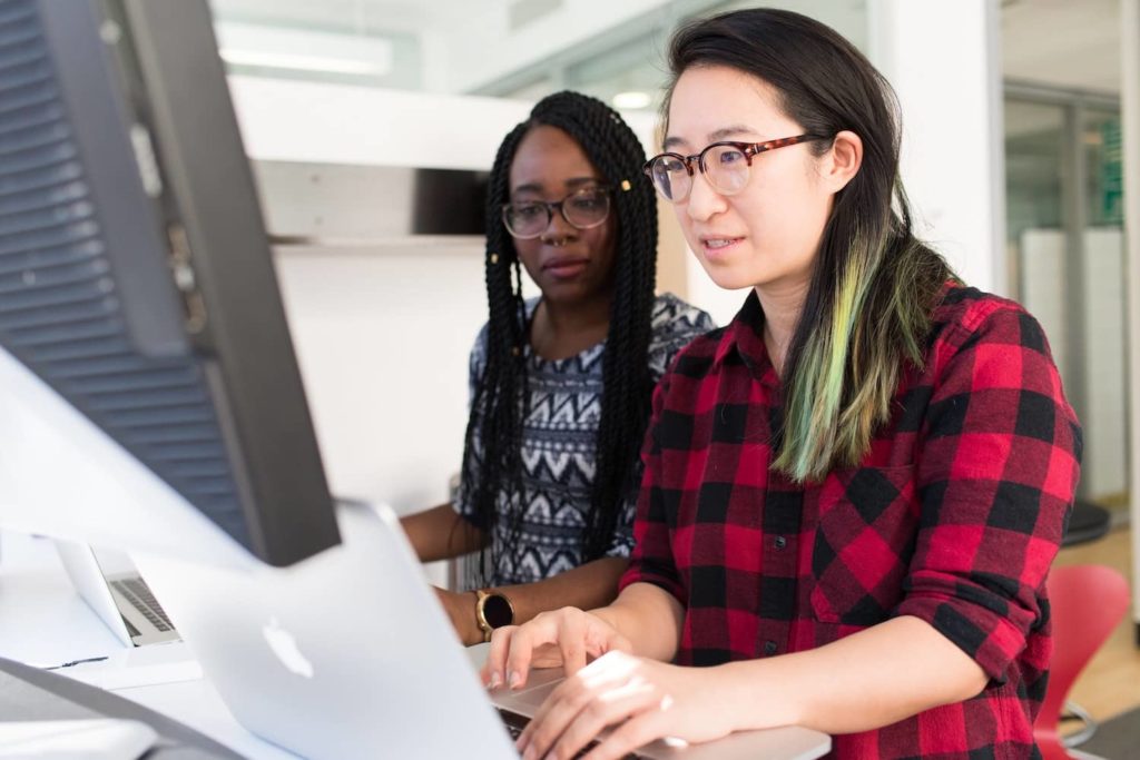 Two women reading marketing newsletters on a laptop